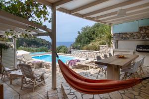 a hammock on a patio with a swimming pool at Villa Christianna Studios in Agios Nikitas