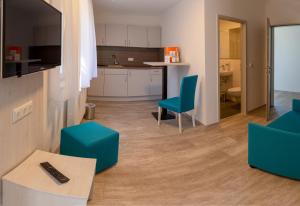 a living room with blue chairs and a kitchen at Kloster Maria Hilf in Bühl