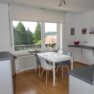 uma cozinha com uma mesa e cadeiras brancas e uma janela em Ferienwohnung Jürgen Brill em Eppelborn