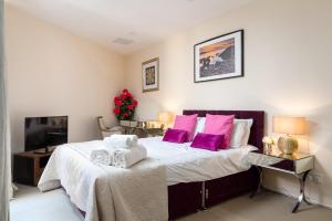 ein Schlafzimmer mit einem großen Bett mit lila Kissen in der Unterkunft 2 Bed Off Regent St in London
