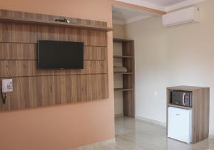 a living room with a flat screen tv on a wall at Pousada Mirante das Águas in Monte Sião