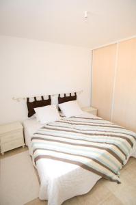 a white bedroom with a large bed with striped sheets at Alzitone in Ghisonaccia