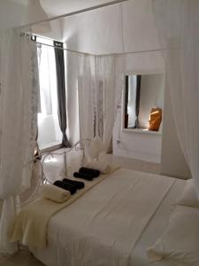 ein weißes Schlafzimmer mit einem weißen Himmelbett und einem Spiegel in der Unterkunft Casa Giordano Bruno in Tarquinia