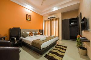 um quarto com uma cama, uma televisão e um sofá em Budget Inn Service Apartments - Tiger Plaza em Vengni