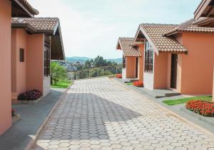 a walkway between two houses with flowers at Pousada Mirante das Águas in Monte Sião