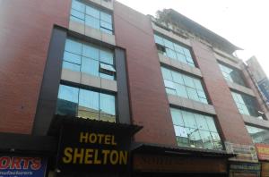 ein großes Gebäude mit Glasfenstern auf einer Straße in der Unterkunft Hotel Shelton in Neu-Delhi