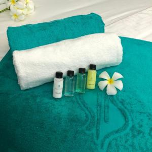 a group of three bottles of soap and a towel and flowers at Village Hideaways & Spas in Fulhadhoo
