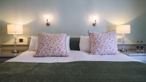 a bed with two pink pillows on top of it at The Wyndham Hotel in Clearwell
