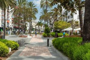 a street with palm trees and a person walking down a sidewalk at Excellent Location Bulevar San Pedro Alcantara-Marbella in Marbella