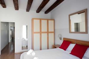 1 dormitorio con cama blanca con almohadas rojas y espejo en My Address in Barcelona Downtown, en Barcelona