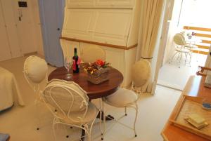 a dining room table with white chairs and a bottle of wine at Appartamento- Murex in Marina di Castagneto Carducci