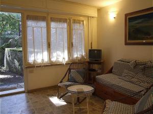 sala de estar con sofá, silla y TV en Bougainvillea 3+3, en Marina di Castagneto Carducci