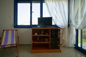 a room with a tv on a stand with windows at Dolphins House in Paralía Avdhíron