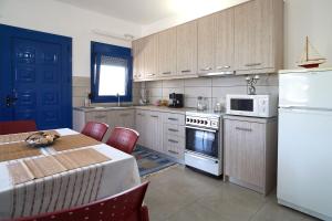 a kitchen with a table and a white refrigerator at Dolphins House in Paralía Avdhíron