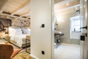 a bedroom with a stone wall and a bed and a bathroom at Villa 5db in Dubrovnik