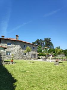 a large stone house with a grass field in front of it at Casa do Pomarelho in Póvoa de Lanhoso