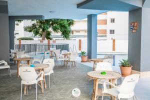 un patio con mesas, sillas y mesas blancas en Apartamentos Palm Beach Club Carihuela, en Torremolinos