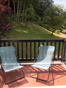 2 chaises assises sur une terrasse couverte avec une clôture dans l'établissement Entre forêt et Mer au Calme, à Trouville-sur-Mer
