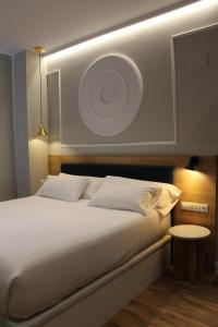 una camera da letto con un grande letto bianco con un piatto appeso al muro di Habital Suites a Jaca