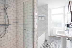 a white bathroom with a shower and a sink at Strandhotel Ahlbeck, a member of Radisson Individuals in Ahlbeck +88 photos