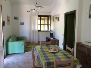 a living room with a table and a green chair at Cottage Su Giudeu in Chia