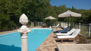a swimming pool with two chairs and an umbrella at Villa La Quercia-Dalia in Sassetta