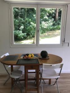 une table avec une assiette de fruits et une fenêtre dans l'établissement Entre forêt et Mer au Calme, à Trouville-sur-Mer