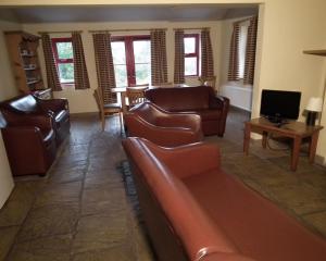 ein Wohnzimmer mit Ledersofas und einem TV in der Unterkunft An Creagán Self Catering Cottages in Greencastle