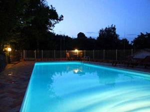 ein großer blauer Pool in einem Garten in der Nacht in der Unterkunft Villa La Quercia-Fresia in Sassetta