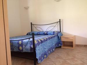 a bedroom with a bed with a blue comforter at Cottage Su Giudeu in Chia