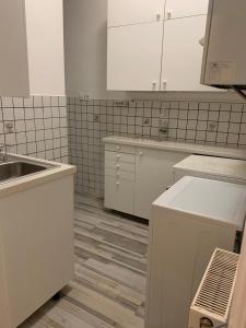 una cocina blanca con armarios blancos y fregadero en Apartment Aman, en Viena