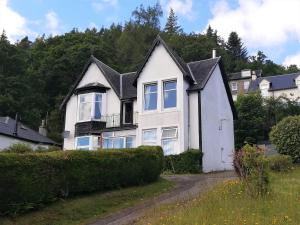 a white house with a black roof at Upper Alta Apartment in Tighnabruaich