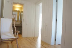 Zimmer mit weißen Wänden, einem Stuhl und einem Spiegel in der Unterkunft Moinhos da Corga in Antigo