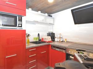 uma cozinha com armários vermelhos e um micro-ondas em Holiday home in Wernigerode near the river em Wernigerode