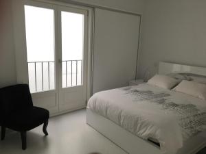 um quarto com uma cama, uma cadeira e uma janela em VIANA é AMOR apartamento no centro histórico em Viana do Castelo