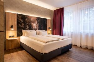 a bedroom with a large bed with a painting on the wall at Arcus Hotel München Messe in Feldkirchen