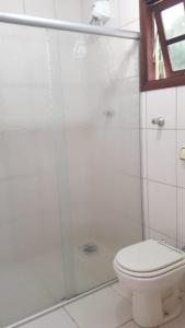 La salle de bains blanche est pourvue d'une douche et de toilettes. dans l'établissement Aguas de São Pedro lugar Familiar e Aconchegante, à São Pedro