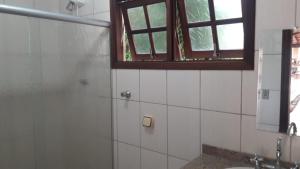 a bathroom with a shower and a sink and a window at Aguas de São Pedro lugar Familiar e Aconchegante in São Pedro