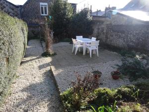 un patio con mesa y sillas en un jardín en Charming French Gite in the heart of quiet Gorron, en Gorron