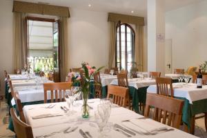 un restaurante con mesas blancas y sillas con flores. en Hotel Vittoria, en Viareggio