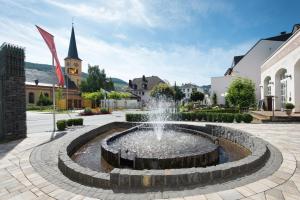 a fountain in the middle of a courtyard with a church at Gästehaus Moselkloster in Trittenheim
