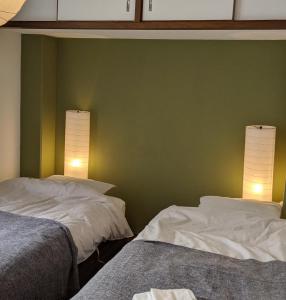 two beds in a room with green walls at roundabout OSAKA in Osaka