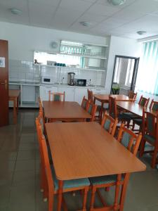 a dining room with wooden tables and chairs and a kitchen at Lánchíd Szálló in Kecskemét