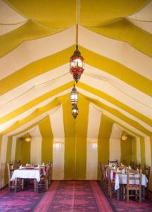 a dining room with yellow and white stripes on the ceiling at Standar camp merzouga in Merzouga