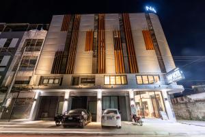 a building with two cars parked in front of it at Nap Hotel in Chiang Rai