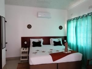 Schlafzimmer mit einem großen Bett und blauen Vorhängen in der Unterkunft Looks cottages self catering apartments in Kasane