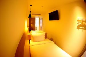 een kleine gele kamer met een bed en kussens bij 26 Inn in Yilan