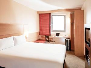 a hotel room with a bed and a desk with a laptop at ibis London City - Shoreditch in London