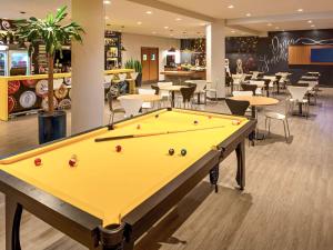 a pool table in a room with tables and chairs at ibis Joinville in Joinville