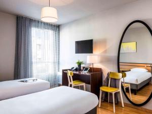 a hotel room with two beds and a mirror at Aparthotel Adagio Access Paris Vanves - Porte de Châtillon in Vanves +36 photos